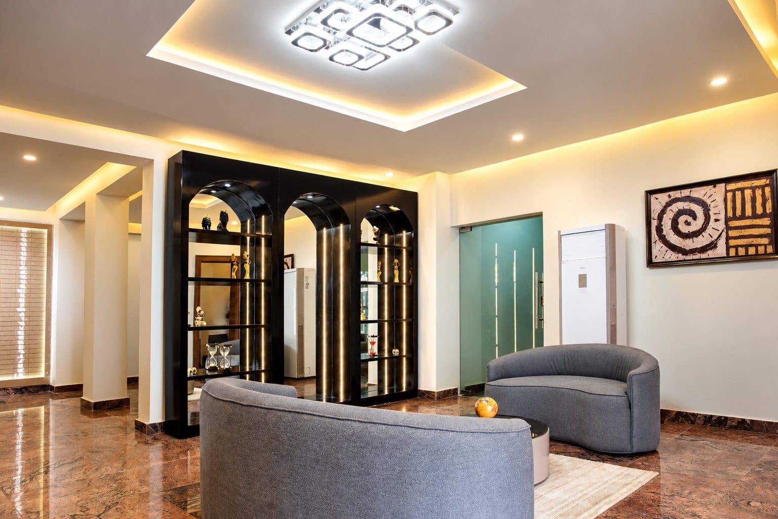 Lounge with curved seating, a display wall and warm cove lighting